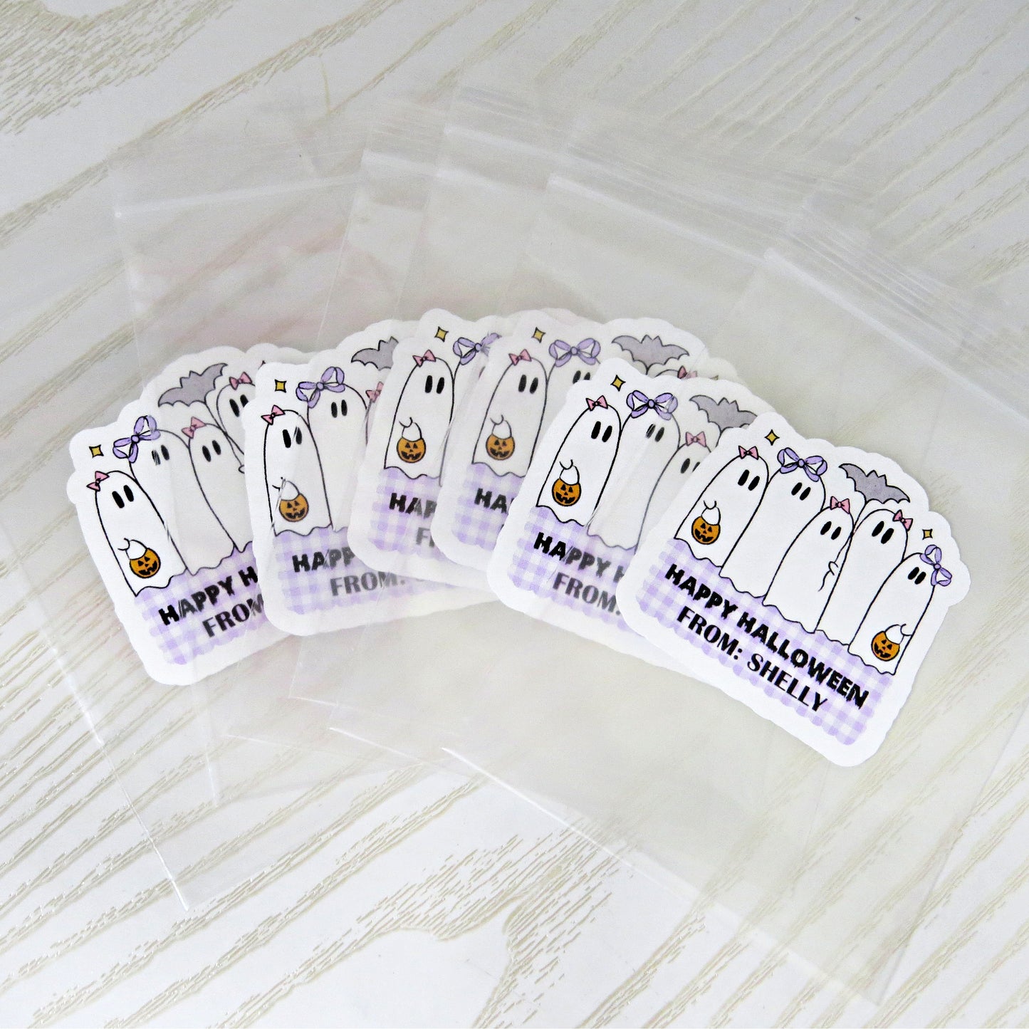 happy halloween stickers with purple gingham background and ghosts holding pumpkins