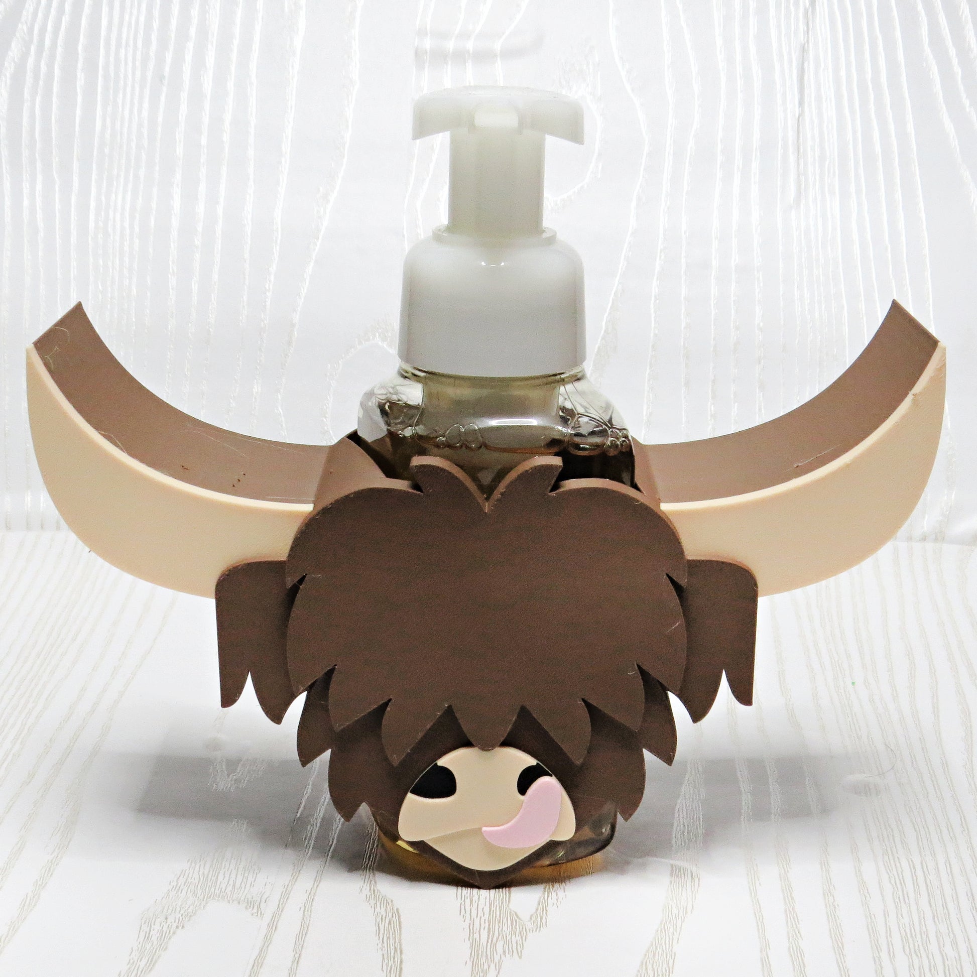 Highland cow foaming soap holder with long horns wrapped around a hand soap bottle rustic farmhouse bathroom countertop decor brown cow sink accessory