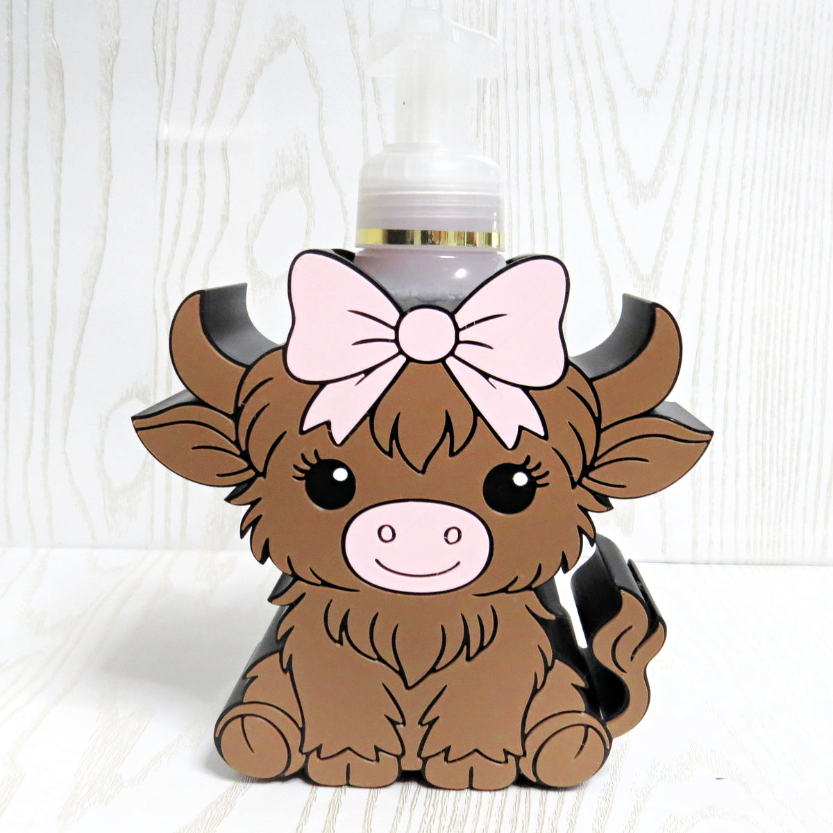 Cute brown highland cow shaped foaming soap bottle holder with pink bow for bathroom decor