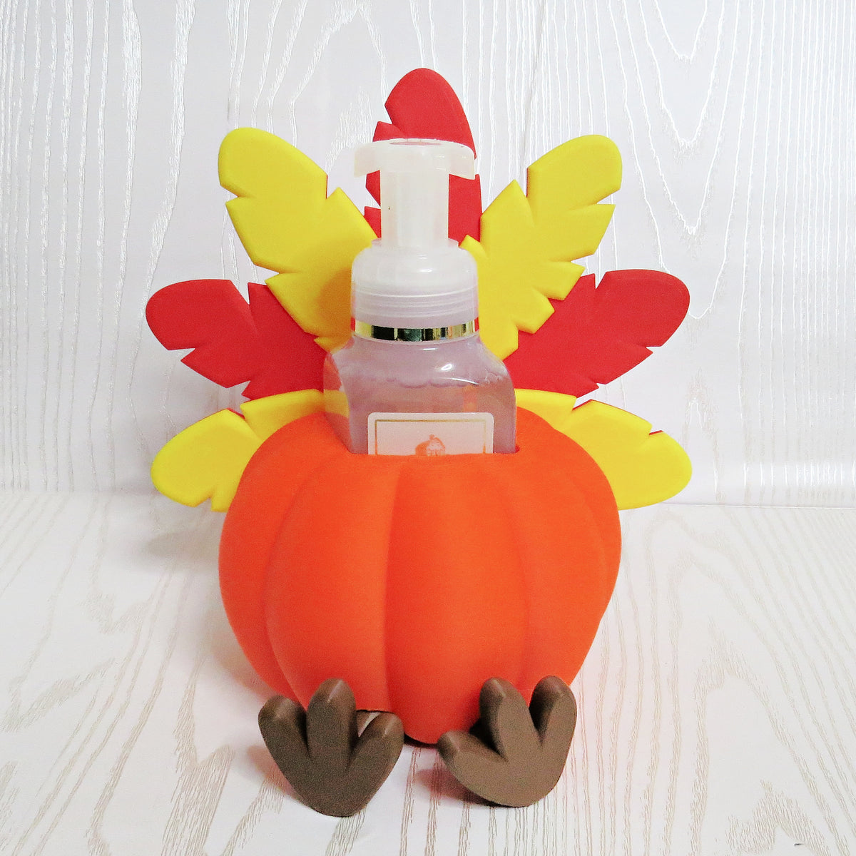Orange pumpkin turkey shaped foaming soap bottle holder with red and yellow feathers for fall decor