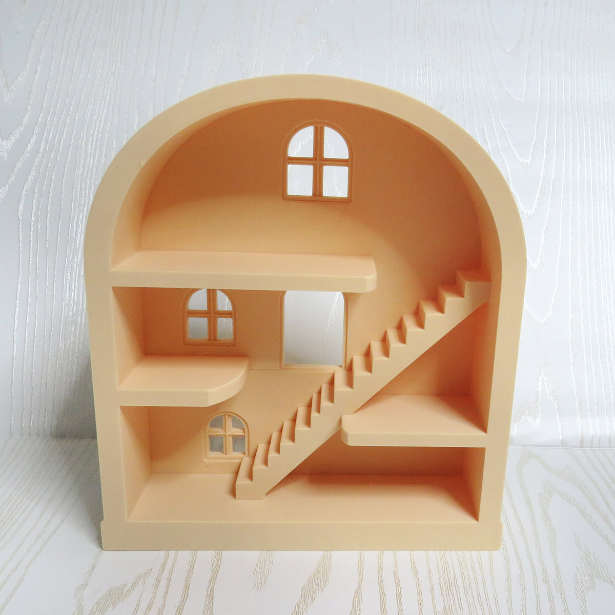 Peach arched mini dollhouse shelf with three levels, a staircase, and cut-out windows