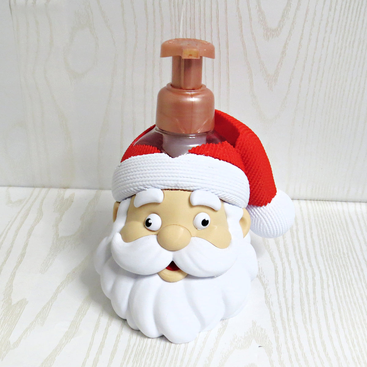 Smiling Santa head foaming soap bottle holder with a red knit hat and soap bottle