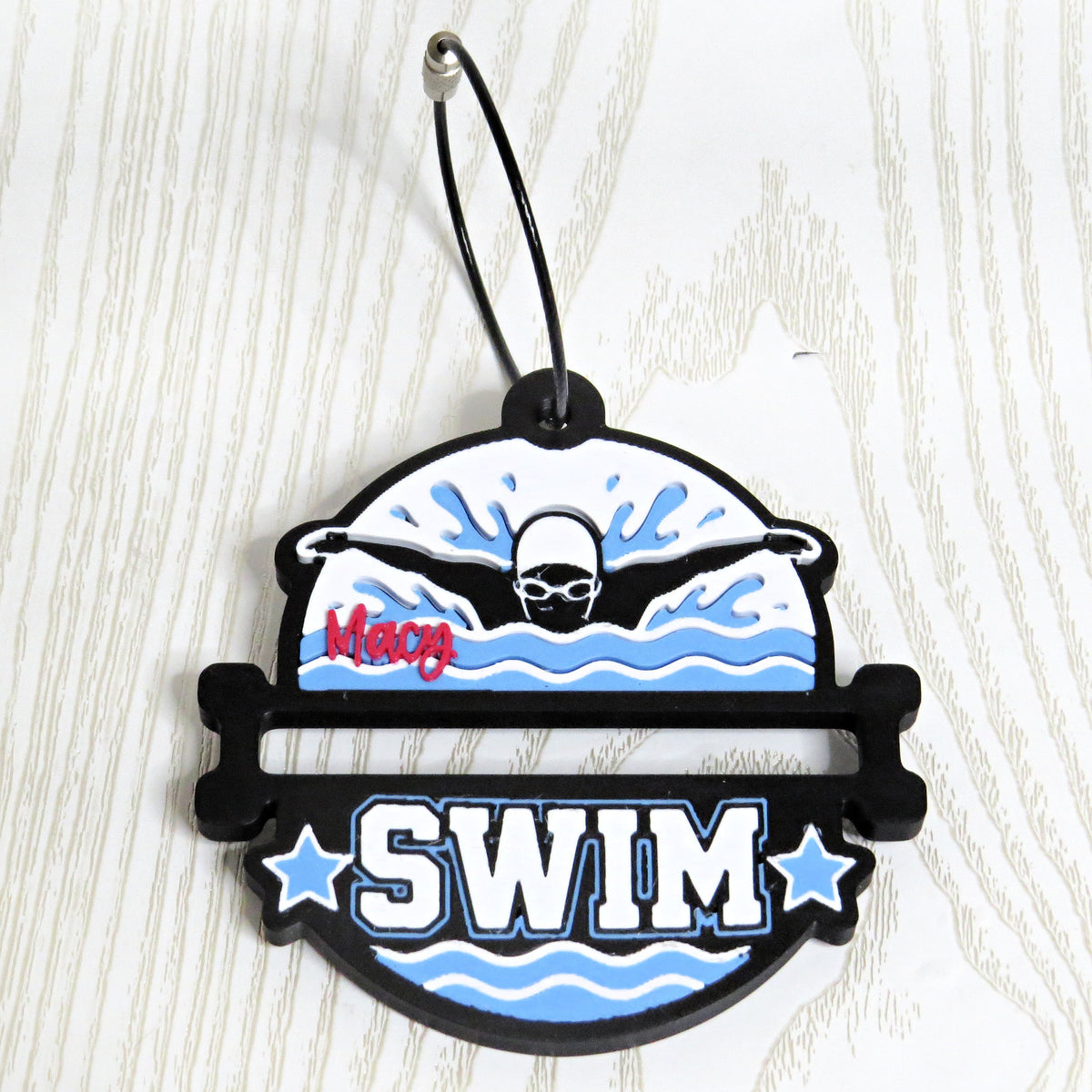 Black, white, and light blue personalized swim bag tag with a butterfly stroke swimmer, name in red, and cable keyring
