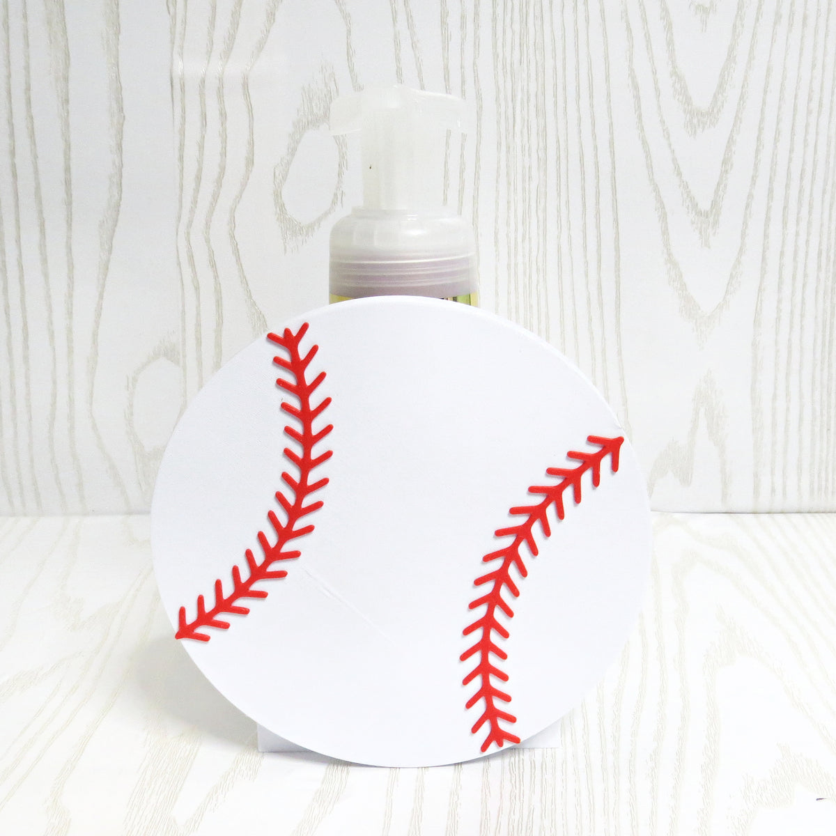 White baseball shaped foaming soap bottle holder with red stitching for bathroom decor