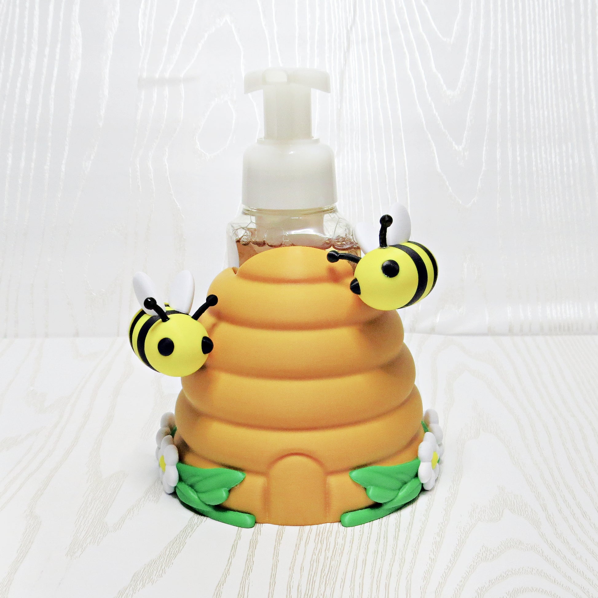 Beehive foaming soap holder with bees and flowers holding soap bottle on kitchen counter