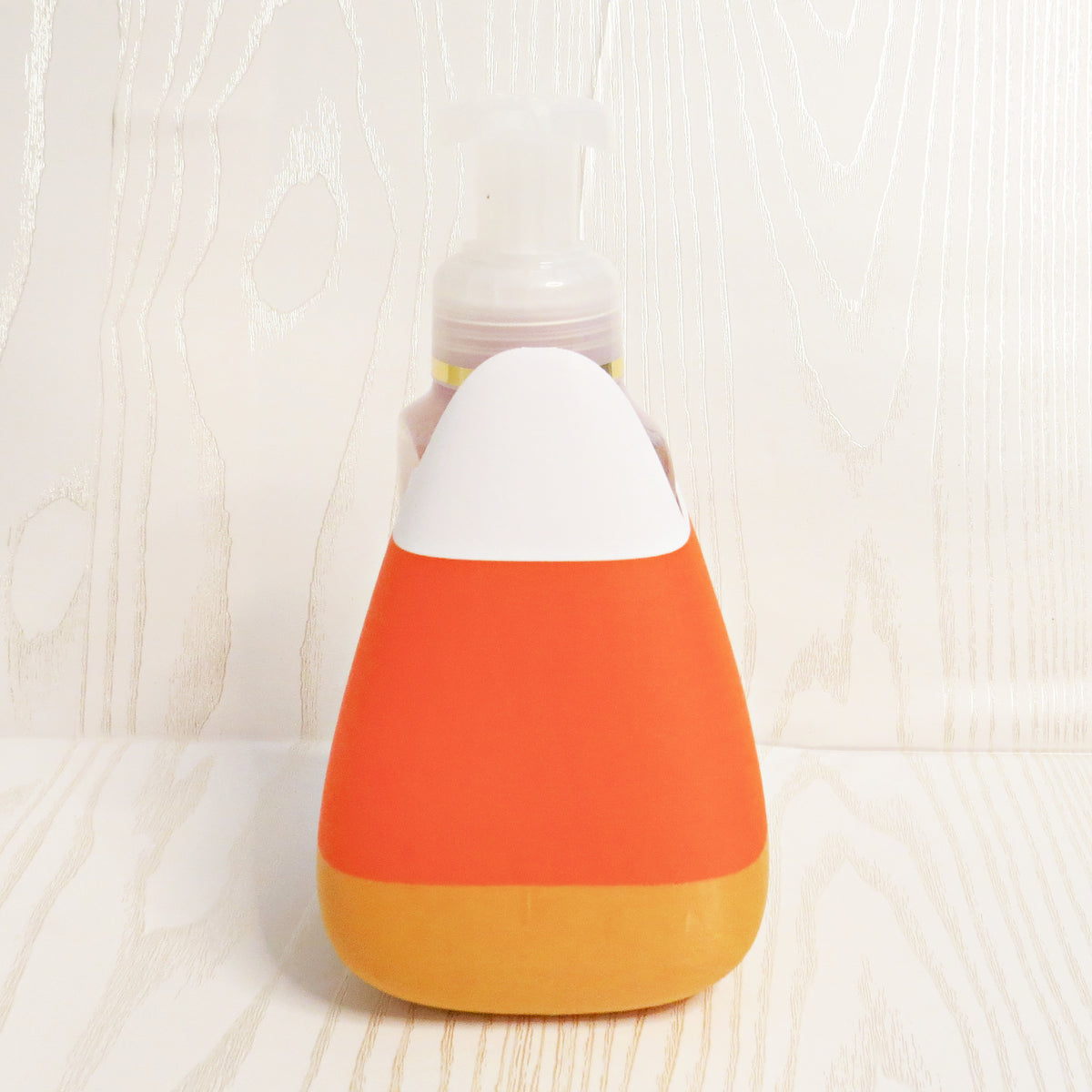 Candy corn shaped foaming soap bottle holder in orange, yellow, and white for Halloween and fall decor
