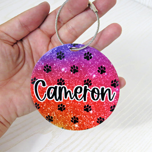 personalized-round-bag-tag-with-name-cameron-dog-paw-print-design-purple-red-orange-glitter-background